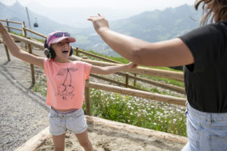 Un enfant danse casque sur les oreilles, les pieds dans le sable et la vue sur les montagnes