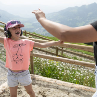 Un enfant danse casque sur les oreilles, les pieds dans le sable et la vue sur les montagnes