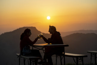 Un couple trinquant sur la terrasse du sommet de Charmey au coucher de soleil
