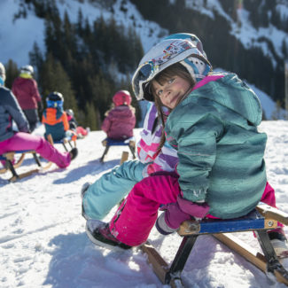 Deux enfants sur une luge au sommet des remontées mécaniques de Charmey