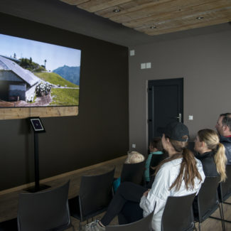 Des visiteurs regardent le film projeté au sommet des remontées mécaniques de Charmey