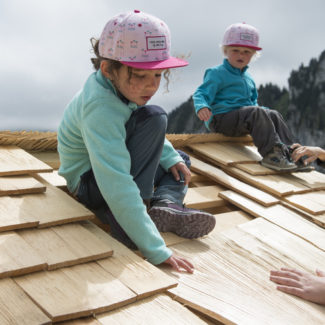 deux petites filles qui s'essaient à la constructions de pavillons sur un petit chalet au sommet des remontées mécaniques de Charmey